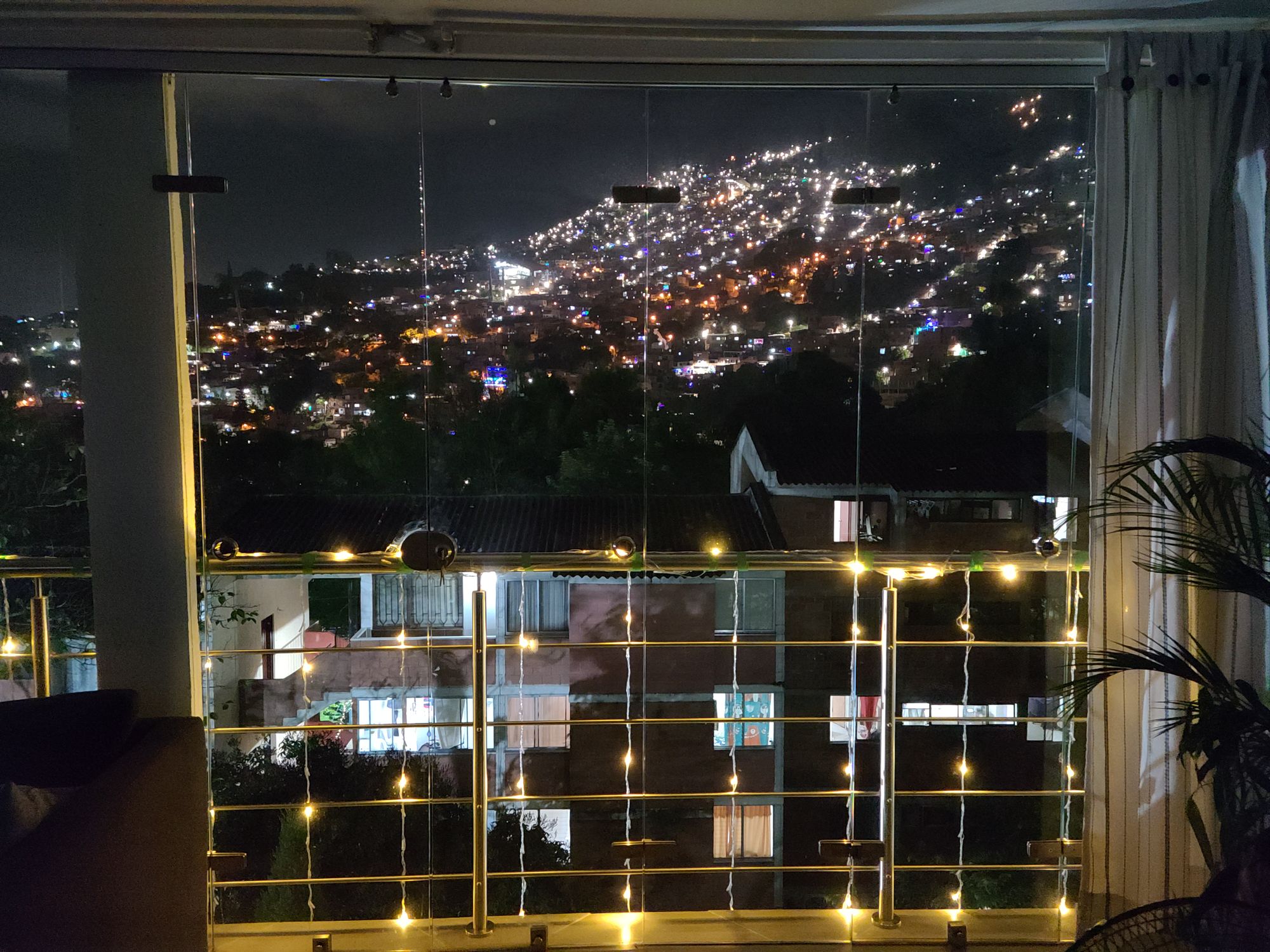 Night view of lights hanging from porch rail and the hill across the valley dotted with lights.