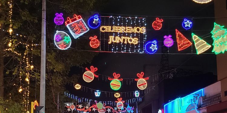 Lights hung above the streets include christmas trees, ornaments, and "celebremos juntos"