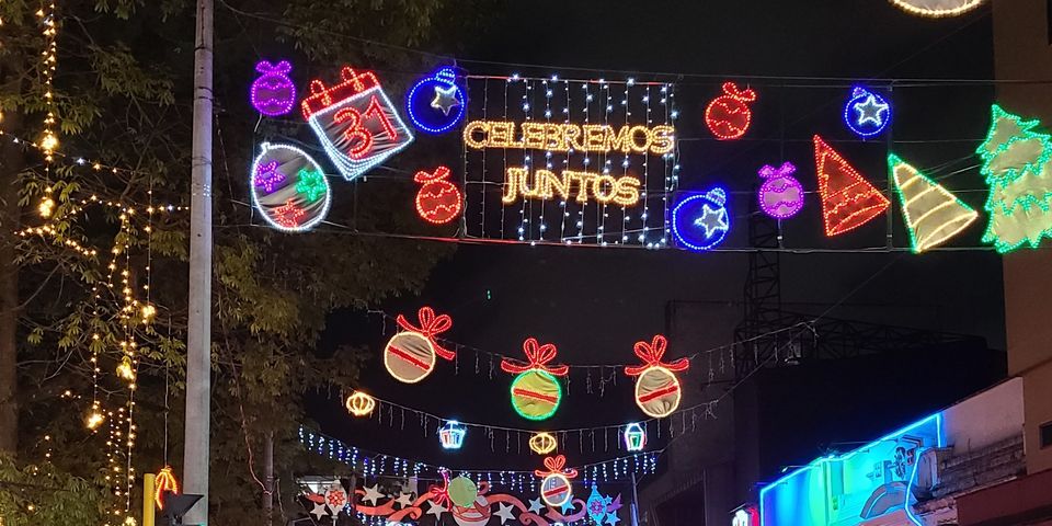 Lights hung above the streets include christmas trees, ornaments, and "celebremos juntos"