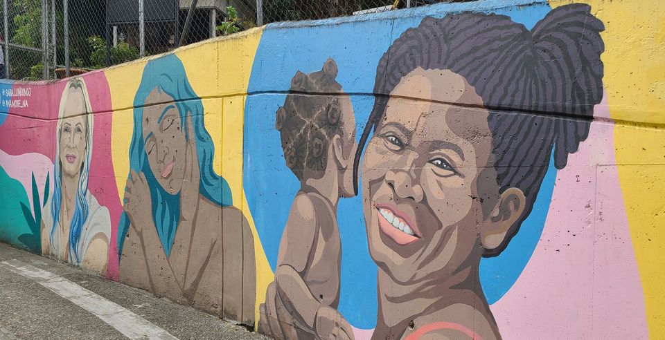 colorful mural of 3 women and one child with skin tones from dark brown to cream. 